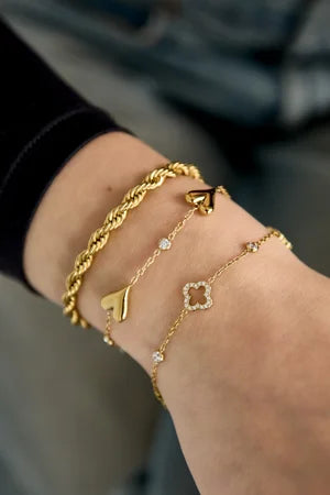 Opengewerkte en belegde klavers en steentjes armband goud