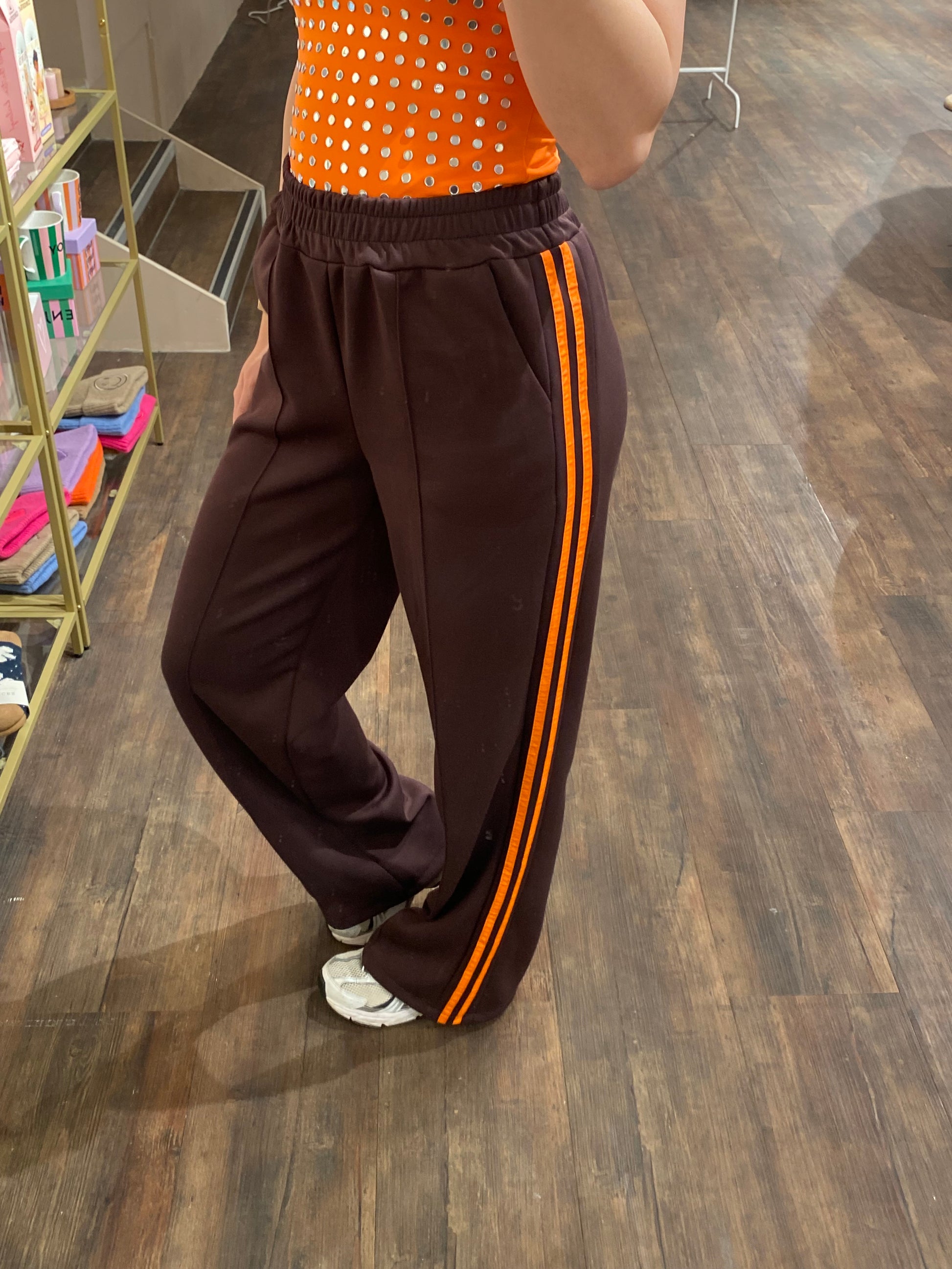 Bruine pantalon met opvallende oranje strepen.