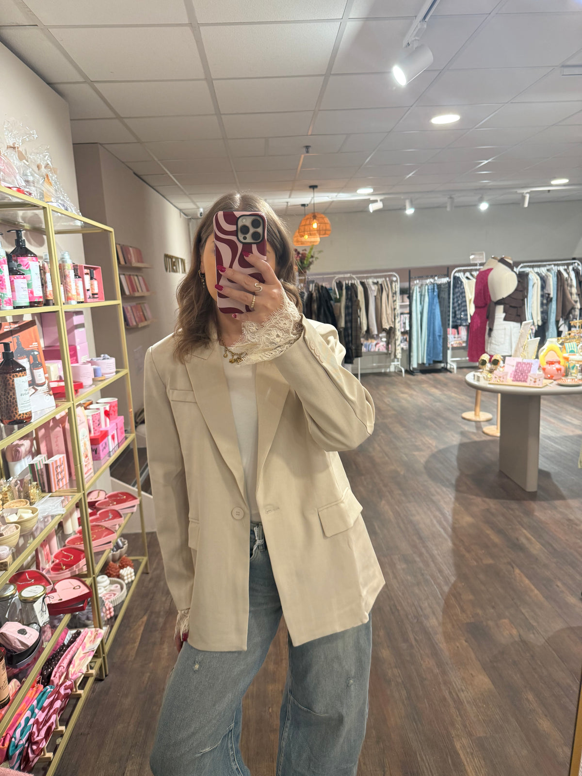 Dames blazer in crème met vrouwelijke kanten details.  