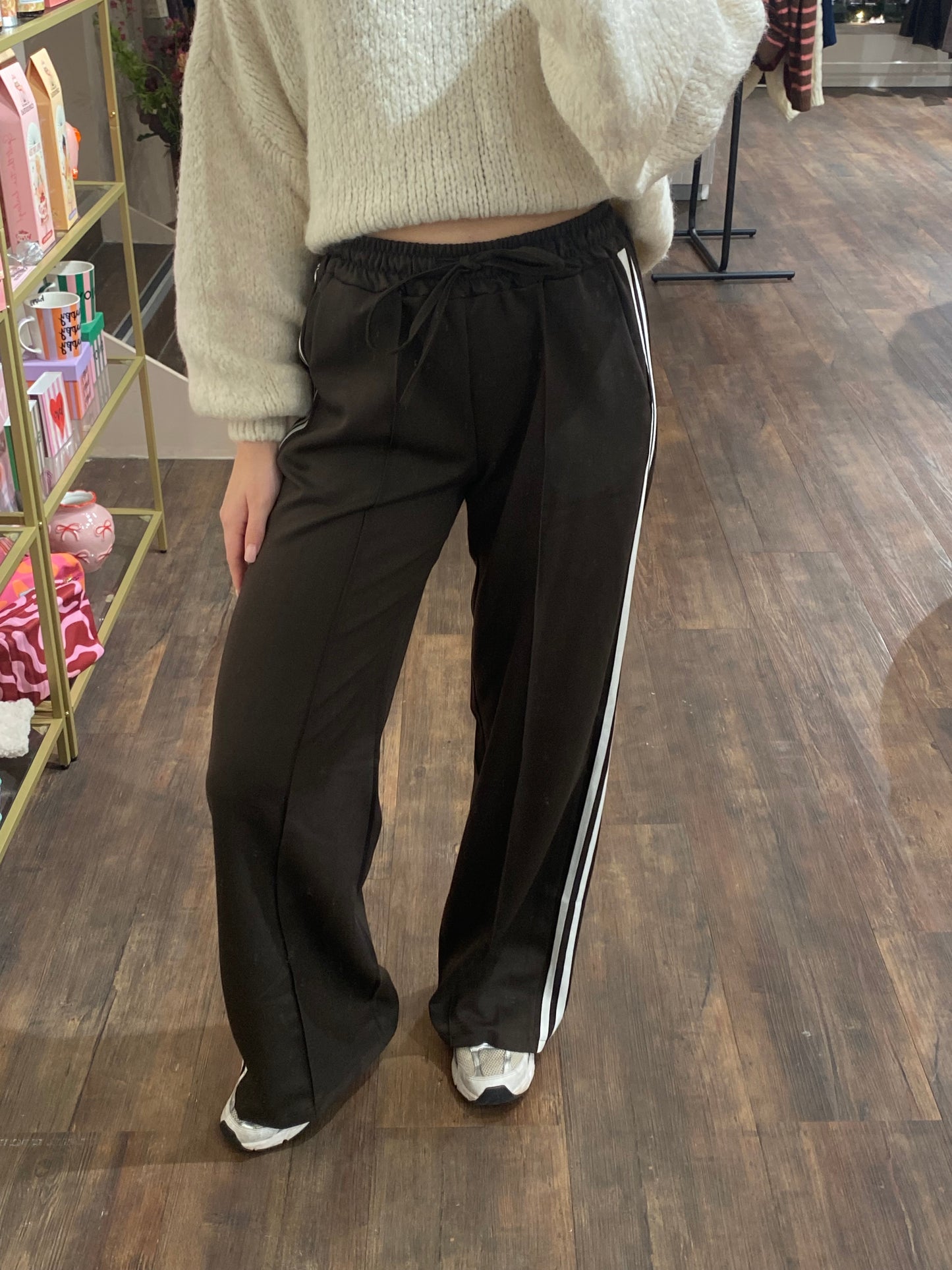 Donkerbruine dames broek met twee witte strepen aan de zijkant.