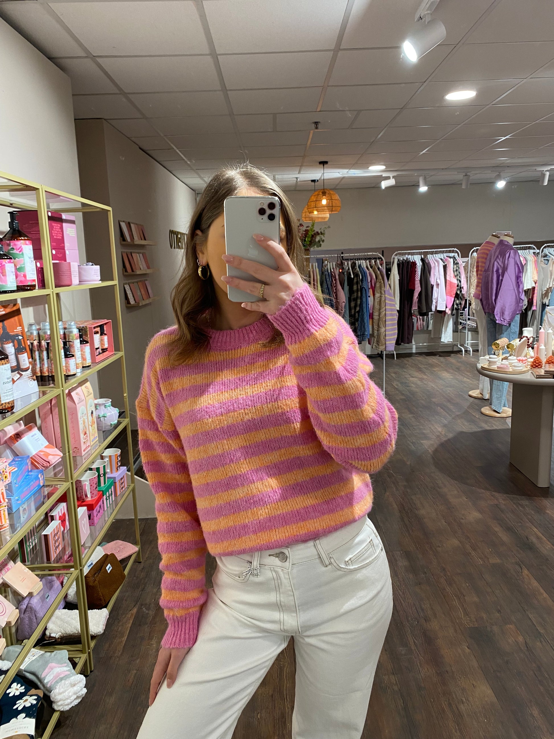 Gestreepte trui in oranje en roze tinten.