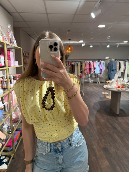 Lichtgele top met zwarte stippen en mouwloos model.