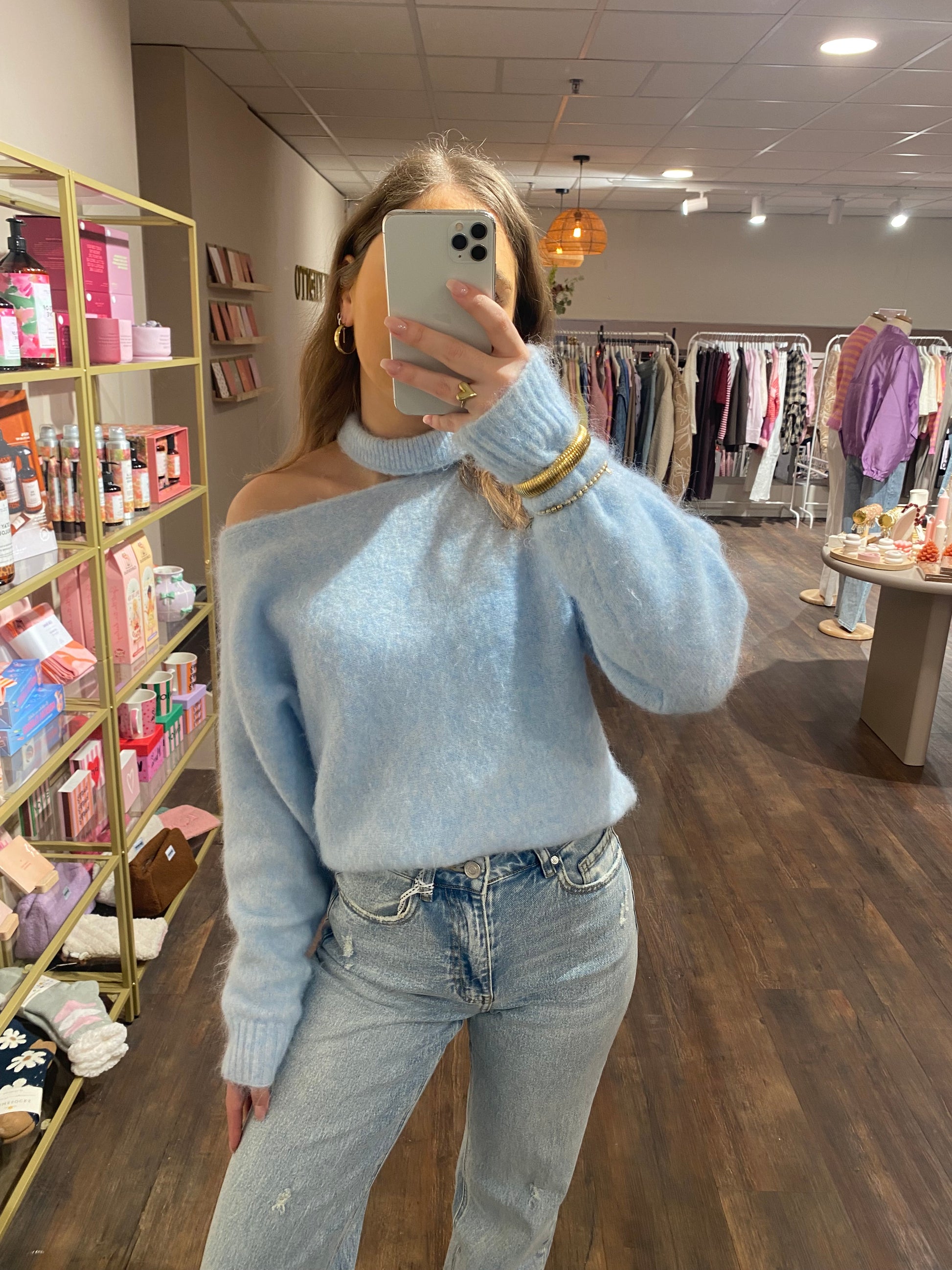 Pastel blauwe trui die off shoulder valt.