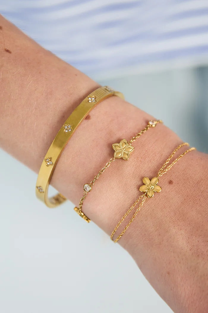 Wisselend patroon van bloemen en steentjes armband goud