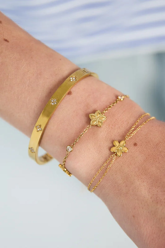 Wisselend patroon van bloemen en steentjes armband goud