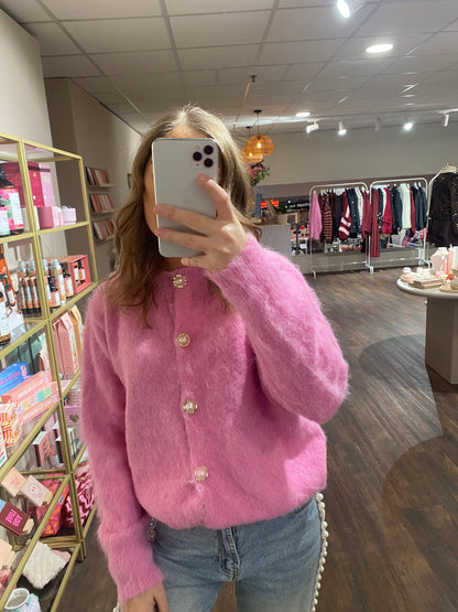 Roze damesvest met parelknopen en zachte stof.