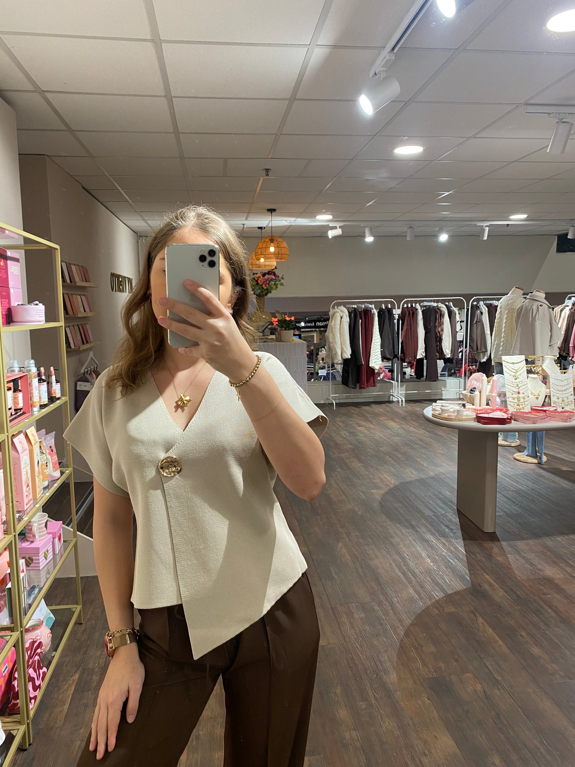 Elegant beige shirt met asymmetrische snit en statement knoop.