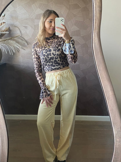 Model draagt stijlvolle outfit; mesh top met luipaardprint en flared mouwen